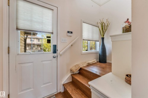 Entryway featuring a white paneled door with window, adjacent window, wood-finish flooring, and a white handrail - 3032 31 Avenue Nw, Edmonton, AB - Indoor Photo Showing Other Room