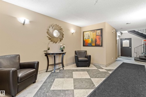 Tiled flooring with contrasting pattern, neutral wall tones, and wall-mounted sconces - #404 11103 84 Av Nw, Edmonton, AB - Indoor Photo Showing Other Room
