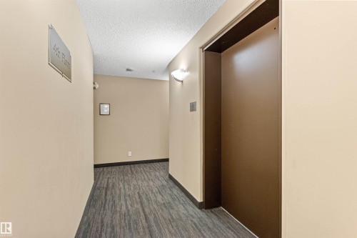 Entryway featuring wood-finish flooring, neutral wall paint, and wall-mounted sconces - #404 11103 84 Av Nw, Edmonton, AB - Indoor Photo Showing Other Room