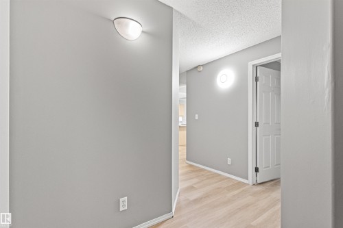 Light gray wall paint, wood-finish flooring, white baseboards, and two wall-mounted light fixtures - #404 11103 84 Av Nw, Edmonton, AB - Indoor Photo Showing Other Room