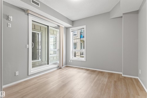Light wood-finish flooring, white trim, and a sliding glass door - #404 11103 84 Av Nw, Edmonton, AB - Indoor Photo Showing Other Room