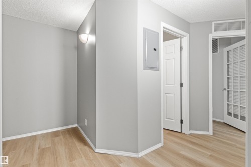 Wood-finish flooring, light gray wall paint, and white trim throughout - #404 11103 84 Av Nw, Edmonton, AB - Indoor Photo Showing Other Room