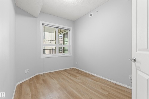 Light wood-finish flooring, white trim, and a window with a white frame - #404 11103 84 Av Nw, Edmonton, AB - Indoor Photo Showing Other Room