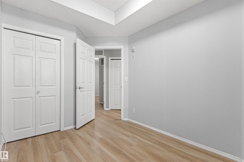 Light gray painted walls, wood-finish flooring, white panel doors, and recessed ceiling details - #404 11103 84 Av Nw, Edmonton, AB - Indoor Photo Showing Other Room
