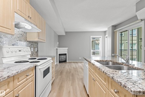 Kitchen featuring granite countertops, wood-finish cabinetry, a double basin stainless steel sink, and a white electric range - #404 11103 84 Av Nw, Edmonton, AB - Indoor Photo Showing Kitchen With Double Sink