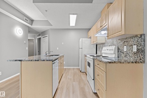 Kitchen featuring light wood-finish cabinetry, granite countertops, and a white appliance package - #404 11103 84 Av Nw, Edmonton, AB - Indoor Photo Showing Kitchen