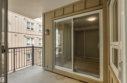 Private balcony with concrete flooring, black metal railing, and exterior wall lantern - #404 11103 84 Av Nw, Edmonton, AB - Outdoor With Balcony With Exterior