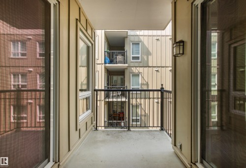 Balcony with concrete flooring, black metal railing, and an exterior wall lantern - #404 11103 84 Av Nw, Edmonton, AB - Outdoor With Balcony With Exterior