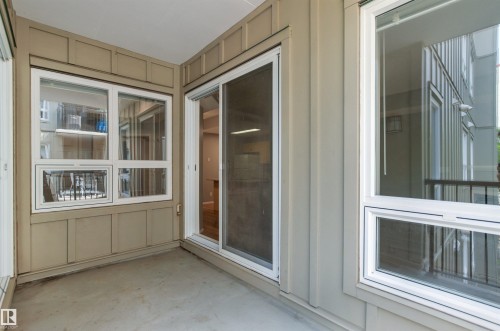 Covered outdoor space featuring a concrete surface, white-framed windows, and a sliding glass door - #404 11103 84 Av Nw, Edmonton, AB - Outdoor With Exterior