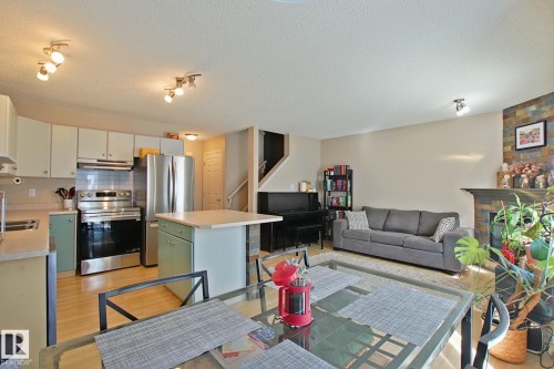 Open-concept living area featuring a kitchen with stainless steel appliances, a center island, and wood-finish flooring - #42 4350 23 St Nw, Edmonton, AB - Indoor Photo Showing Kitchen