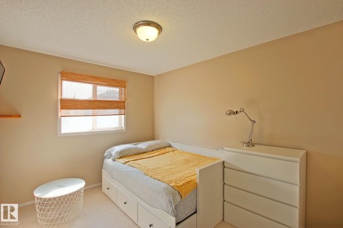 Window with bamboo blinds, wall-mounted shelving, built-in storage bed, four-drawer dresser, and flush-mount ceiling light fixture - #42 4350 23 St Nw, Edmonton, AB - Indoor Photo Showing Other Room