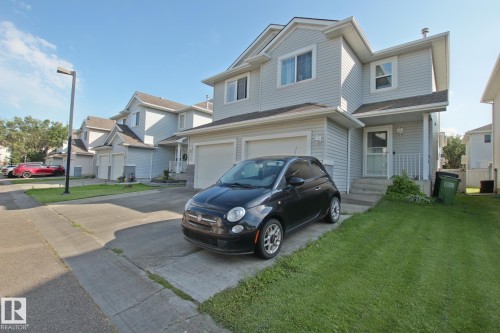 Two-story residence with light-colored siding, an attached garage, and a concrete driveway - #42 4350 23 St Nw, Edmonton, AB - Outdoor With Facade