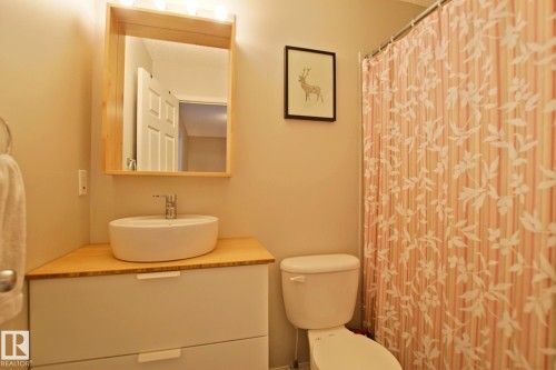 Modern vanity with a rectangular vessel sink, wood-finish countertop, and light-toned cabinetry - #42 4350 23 St Nw, Edmonton, AB - Indoor Photo Showing Bathroom