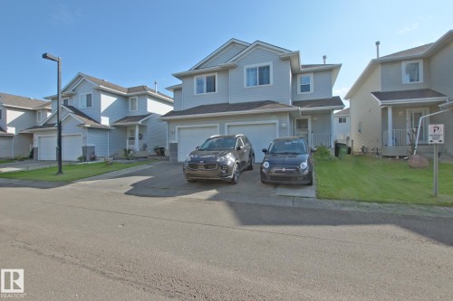 Light blue siding exterior with white window trim, dual garage doors, and a paved driveway - #42 4350 23 St Nw, Edmonton, AB - Outdoor With Facade