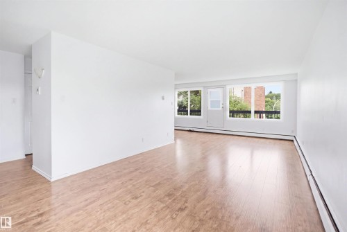 Expansive room featuring wood-finish flooring, white walls, and a large window providing ample natural illumination - 7825 159 Street Nw, Edmonton, AB - Indoor