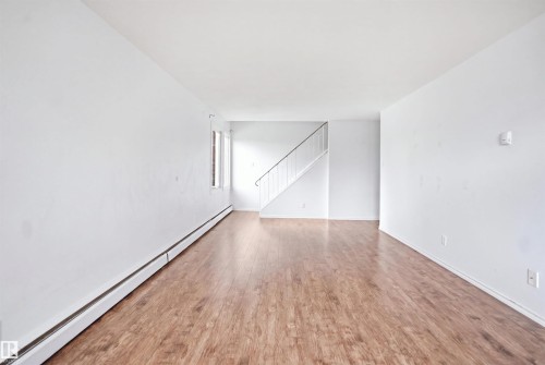 Wood-finish flooring, white walls, and a staircase with a white railing - 7825 159 Street Nw, Edmonton, AB - Indoor Photo Showing Other Room