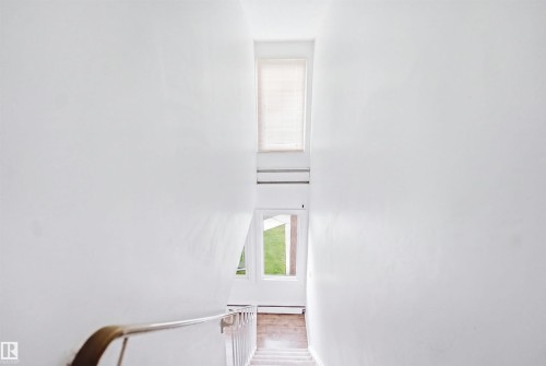 Upper-level window, lower-level windows, interior wall with a handrail, and carpeted stairs - 7825 159 Street Nw, Edmonton, AB -  Photo Showing Other Room