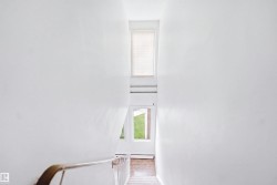 Upper-level window, lower-level windows, interior wall with a handrail, and carpeted stairs - 