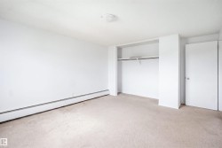 Neutral-toned carpeting, white walls, and a built-in closet with shelving and hanging rod - 