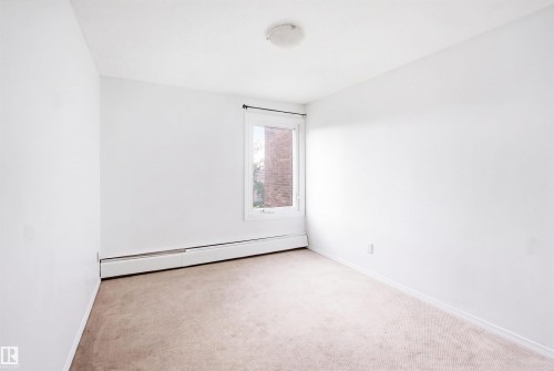 Neutral wall paint, carpet flooring, baseboard heating, single window with dark hardware, and a ceiling-mounted light fixture - 7825 159 Street Nw, Edmonton, AB - Indoor Photo Showing Other Room
