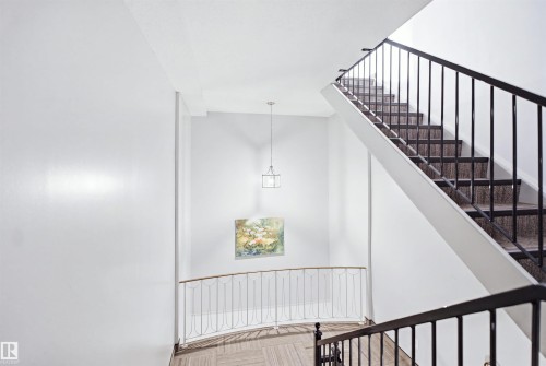Stairwell featuring metal railings, pendant lighting, and carpeted stairs - 7825 159 Street Nw, Edmonton, AB - Indoor Photo Showing Other Room