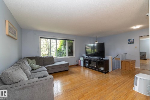 Hardwood flooring throughout, large window, and a built-in media console with an electric fireplace - 14215 78 Street Nw, Edmonton, AB - Indoor Photo Showing Living Room