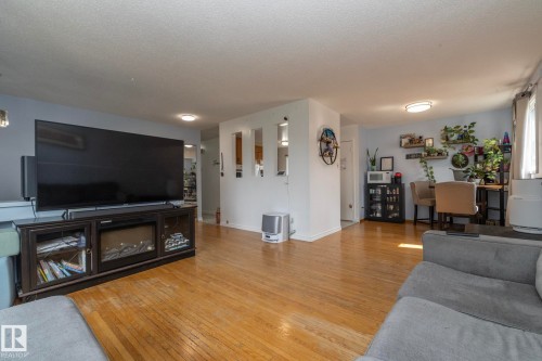 Spacious living area showcasing warm wood-finish flooring, recessed ceiling lighting, and a media console with storage - 14215 78 Street Nw, Edmonton, AB - Indoor Photo Showing Living Room