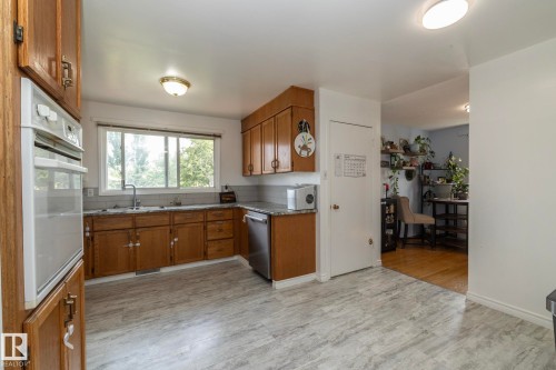 Kitchen featuring wood cabinetry, stainless steel dishwasher, an integrated wall oven, and light-toned flooring - 14215 78 Street Nw, Edmonton, AB - Indoor Photo Showing Kitchen With Double Sink