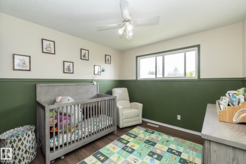 Wood-finish flooring with a neutral wall color and contrasting green lower wall - 14215 78 Street Nw, Edmonton, AB - Indoor Photo Showing Bedroom