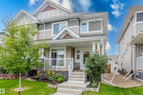 Multi-story residence featuring composite siding, a covered front porch with white columns, and a stone facade accent - 124 Cy Becker Boulevard Nw, Edmonton, AB - Outdoor With Deck Patio Veranda With Facade