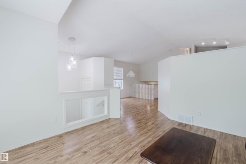 Interior space featuring wood-finish flooring, white walls, and a multi-level layout - 1694 Tompkins Wynd Nw, Edmonton, AB - Indoor Photo Showing Other Room