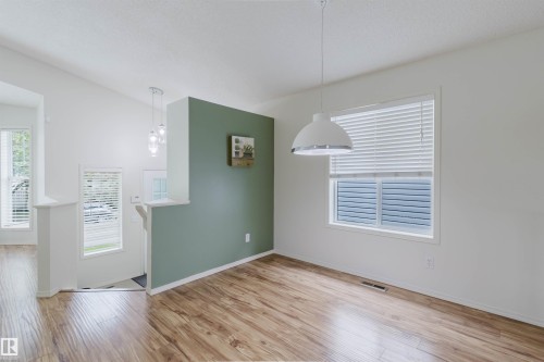 Interior space featuring wood-finish flooring and a white window with horizontal blinds - 1694 Tompkins Wynd Nw, Edmonton, AB - Indoor Photo Showing Other Room