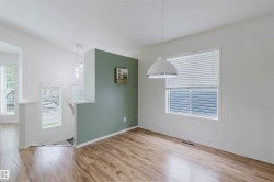 Interior space featuring wood-finish flooring and a white window with horizontal blinds - 