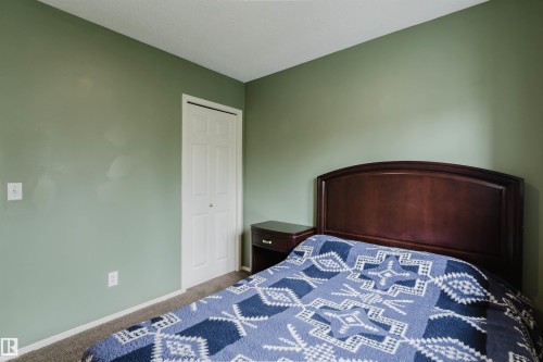 Bedroom featuring a bi-fold closet door, neutral carpet flooring, and light green wall paint - 1694 Tompkins Wynd Nw, Edmonton, AB - Indoor Photo Showing Bedroom