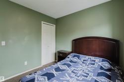 Bedroom featuring a bi-fold closet door, neutral carpet flooring, and light green wall paint - 