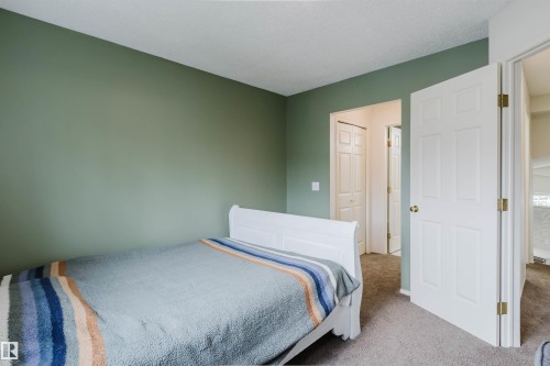 Interior room featuring a neutral carpet flooring, a single paneled door, and a bi-fold closet door - 1694 Tompkins Wynd Nw, Edmonton, AB - Indoor Photo Showing Bedroom