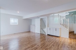 Spacious lower-level area featuring wood-finish flooring, white walls, and recessed lighting - 