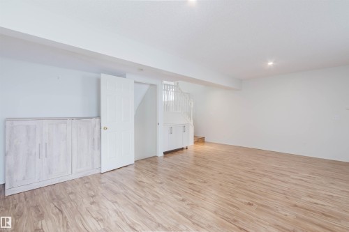 Spacious room featuring wood-finish flooring, recessed lighting, and white painted walls - 1694 Tompkins Wynd Nw, Edmonton, AB - Indoor Photo Showing Other Room