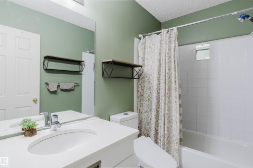 Bathroom featuring a single vanity with an integrated sink, polished chrome faucet, and a large wall mirror - 1694 Tompkins Wynd Nw, Edmonton, AB - Indoor Photo Showing Bathroom