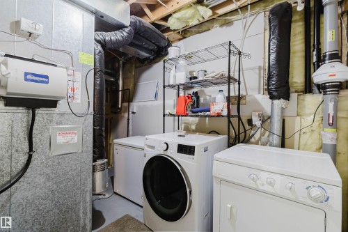 Utility area featuring a front-load washing machine, a white dryer, and a stand-alone freezer - 1694 Tompkins Wynd Nw, Edmonton, AB - Indoor Photo Showing Laundry Room