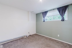 Carpeted interior space featuring a window with integrated blinds, a light green accent wall, and white trim - 