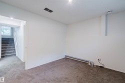Carpeted room featuring white walls, recessed lighting, and a visible staircase with a window - 