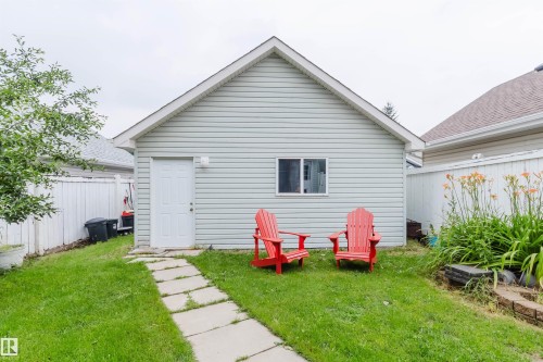 Detached garage featuring light-colored siding, a white access door, and a single window - 1694 Tompkins Wynd Nw, Edmonton, AB - Outdoor