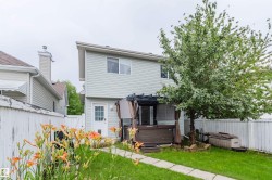 Fenced backyard featuring a walkway, a mature tree, and established plantings - 