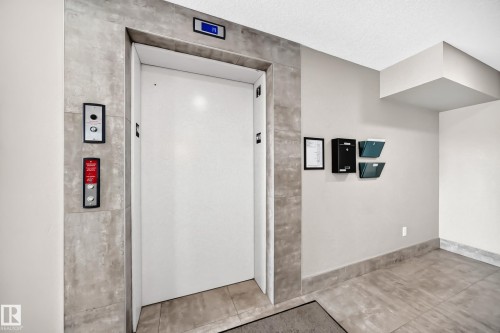 Elevator access within a tiled entryway featuring a recessed ceiling - #322 148 Ebbers Bv Nw, Edmonton, AB - Indoor Photo Showing Other Room