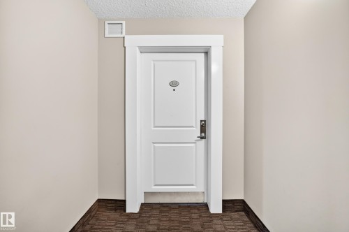 White paneled door with contemporary hardware and substantial door trim - #322 148 Ebbers Bv Nw, Edmonton, AB - Indoor Photo Showing Other Room