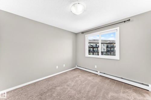 Neutral painted walls, wall-to-wall carpeting, and a white window frame - #322 148 Ebbers Bv Nw, Edmonton, AB - Indoor Photo Showing Other Room