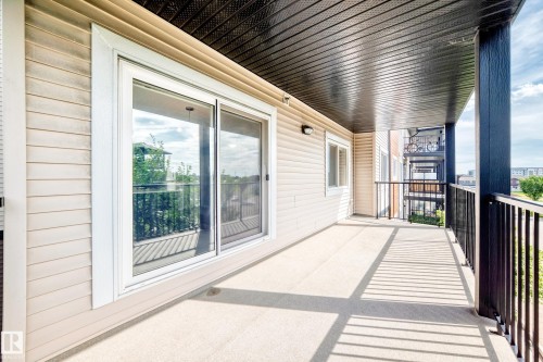 Spacious balcony featuring a dark metal railing, light-toned siding, and a dark soffit ceiling - #322 148 Ebbers Bv Nw, Edmonton, AB - Outdoor With Deck Patio Veranda With Exterior