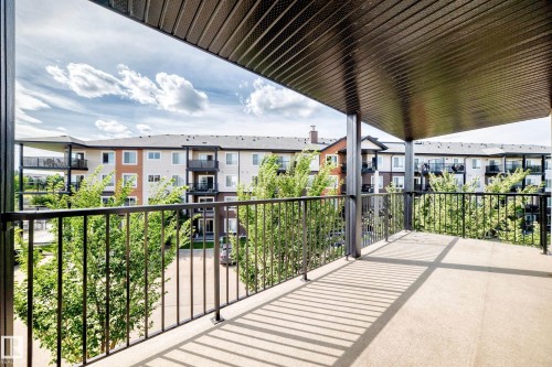Covered balcony with concrete flooring and dark metal railings - #322 148 Ebbers Bv Nw, Edmonton, AB - Outdoor With Balcony With Exterior