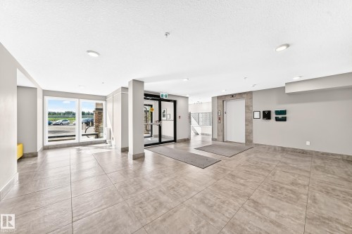 Tile flooring, recessed lighting, expansive windows, glass entry doors, and a built-in elevator - #322 148 Ebbers Bv Nw, Edmonton, AB - Indoor Photo Showing Other Room